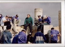 Teacher and high school students having class outdoors among ancient ruins